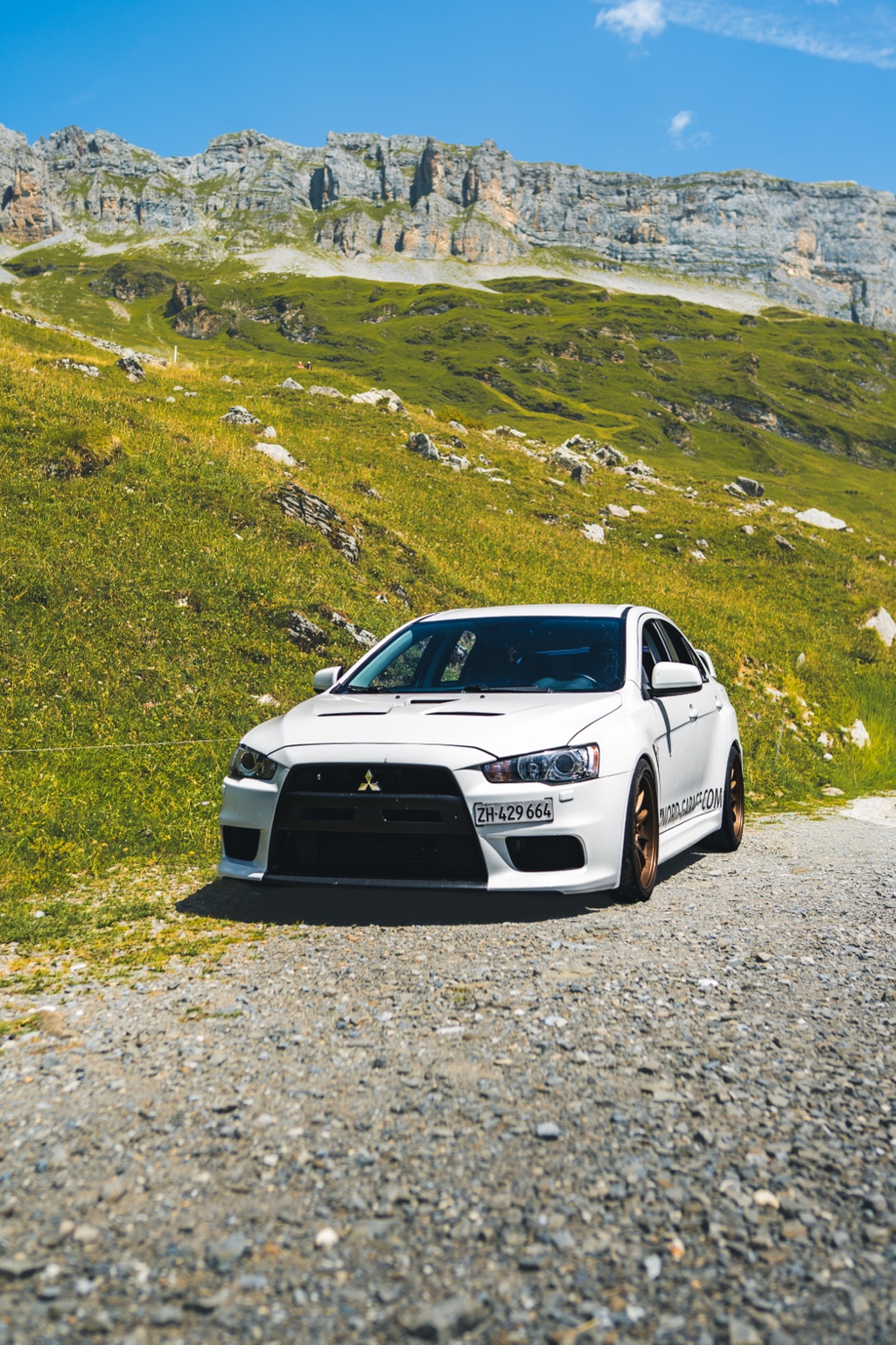 Weisser Mitsubishi vor einer Berglandschaft